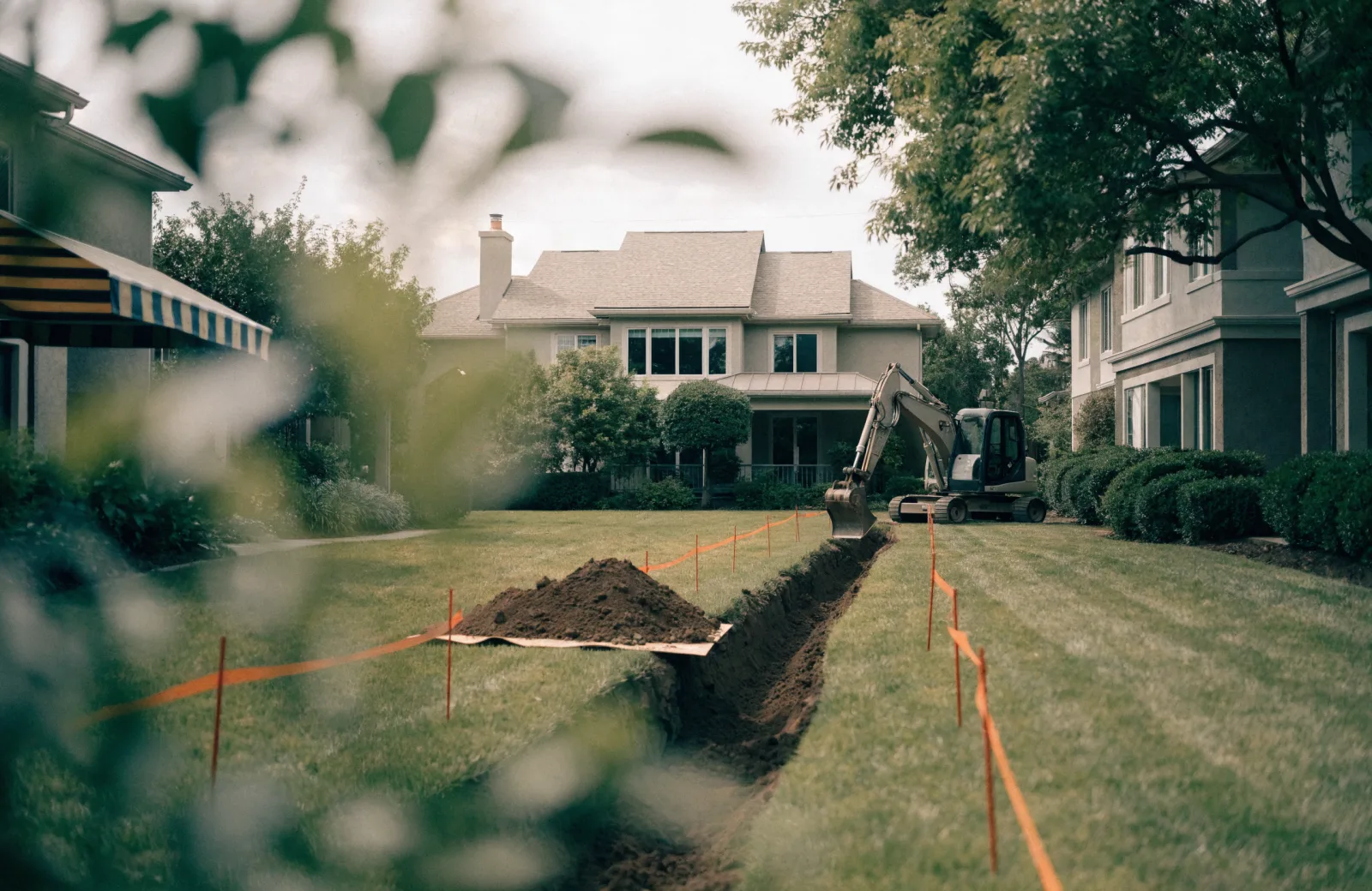 Open sewer lateral trench dug across a residential front lawn toward the street