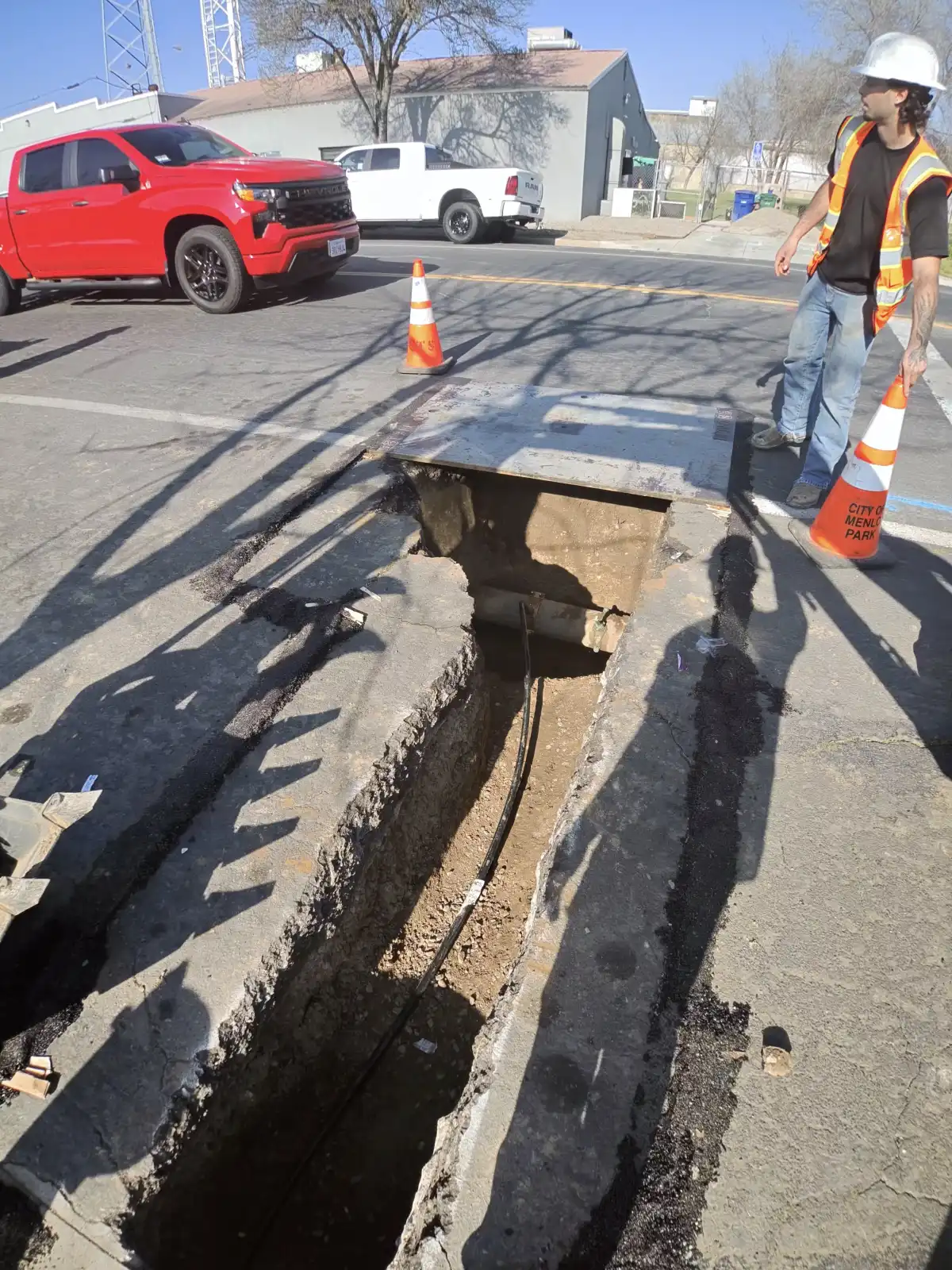 Narrow trench cut through pavement and curb with a new water service line laid in the bottom